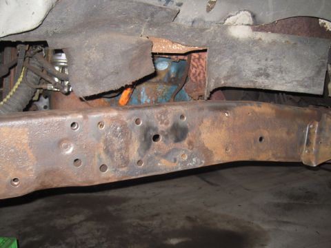 1979 Ford Bronco - Close-up view of a heavily rusted vehicle frame, showing suspension components and undercarriage details.