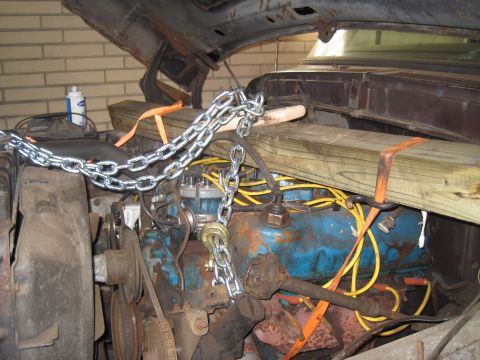 1979 Ford Bronco - Engine bay secured with chains and wooden beams, likely for repair or transport.