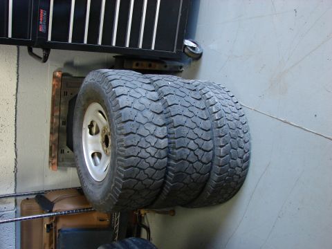 1993 Jeep YJ - A stack of three off-road tires with aggressive tread patterns is visible, mounted on silver rims.