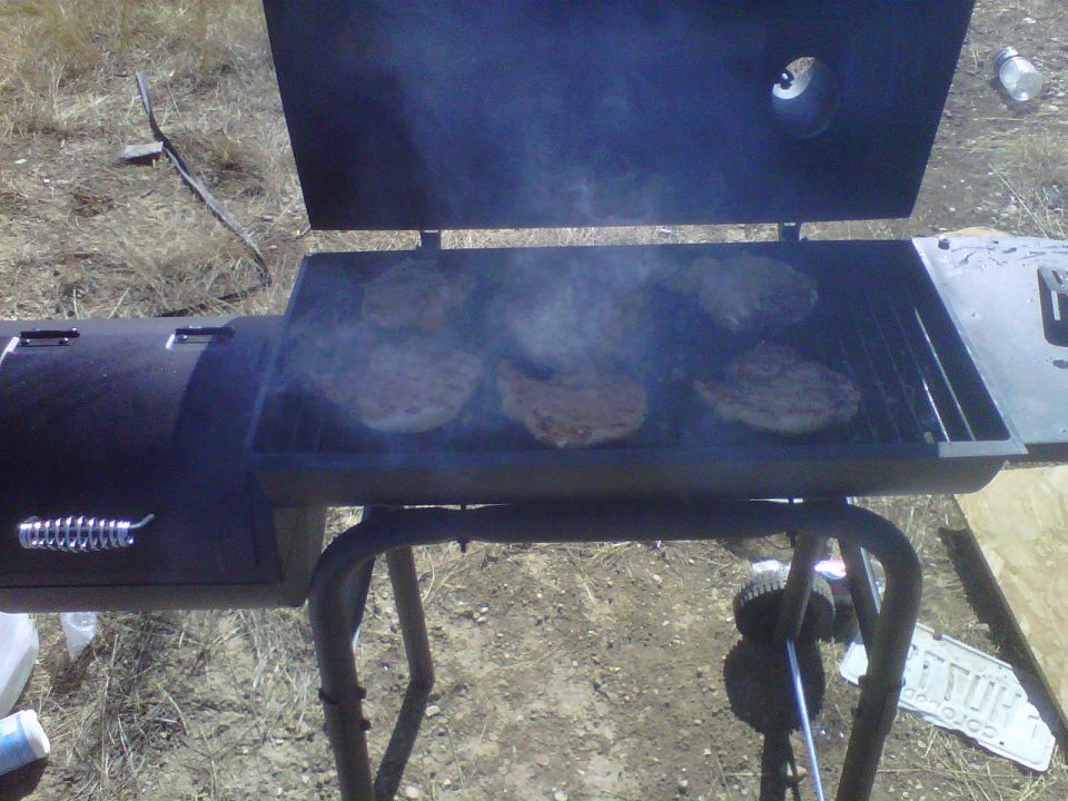 Barbecue grill with burgers smoking on the grates, outdoors