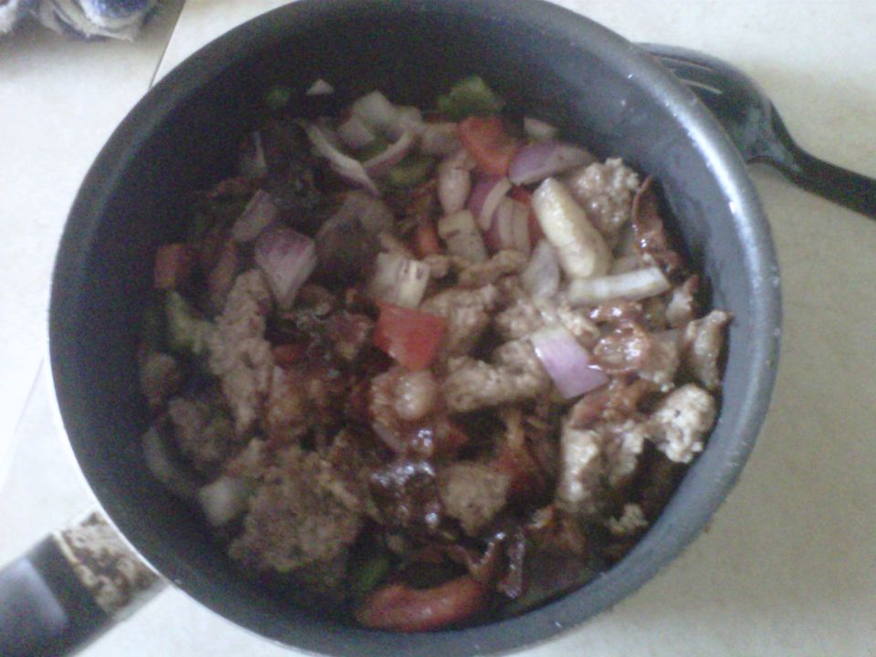 Pot of food with meat, onions, and peppers