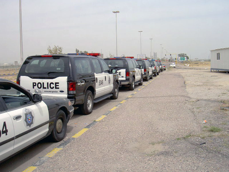 Kuwait police vehicles lined up on a road, including a sedan and several SUVs