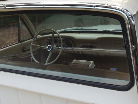 1963 Ford Ranchero - The interior of a 1963 Ford Ranchero shows its beige dashboard and steering wheel, viewed through the passenger window.