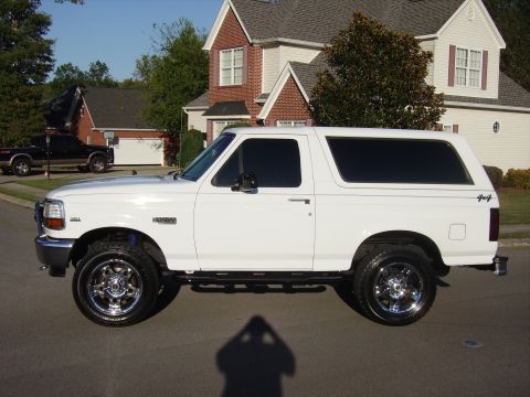 1995 Ford Bronco - Side profile of a white 1995 Ford Bronco SUV with aftermarket wheels.