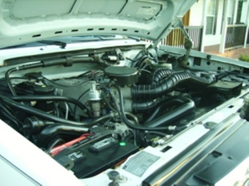 engine bay with hoses, battery, and air intake visible