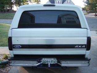 1995 Ford Bronco - The rear of a white Ford Bronco shows a 4x4 badge and a large "SUPERMOTORS" banner across the license plate area.