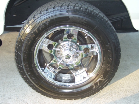 1995 Ford Bronco - Close-up of a chrome wheel and Toyo Country A/T tire on a white vehicle.