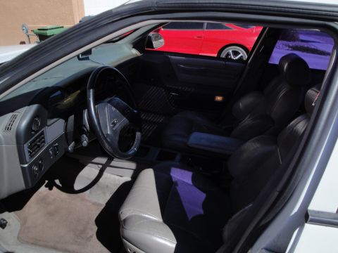 1989 Ford Taurus - The interior of a 1989 Ford Taurus is visible, with a red car seen through the tinted windows.