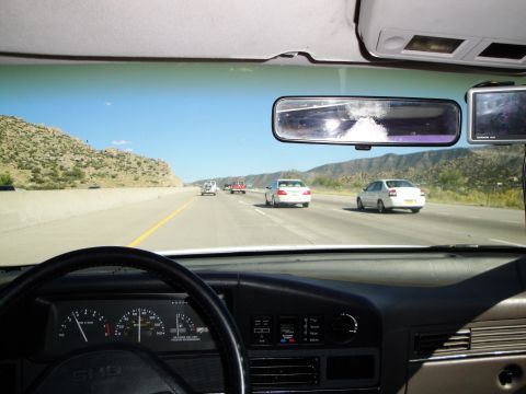 1989 Ford Taurus - Driving on a highway with multiple vehicles visible ahead under a clear blue sky.