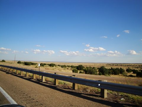 1989 Ford Taurus - A view of a highway guardrail and arid terrain under a clear blue sky with sparse clouds.