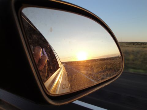 1989 Ford Taurus - Driving into the sunset, with the reflection showing the road ahead and a hand near the window.