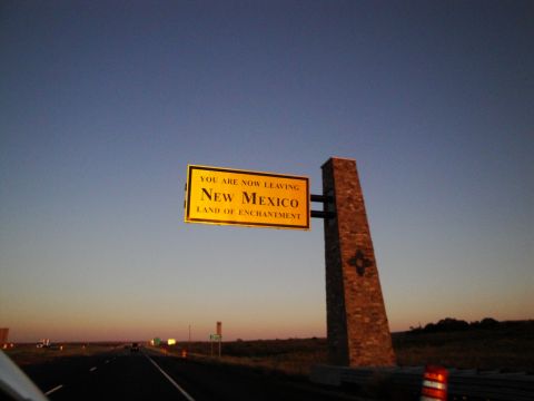 1989 Ford Taurus - A sign indicates the state line as the sun sets over the highway.