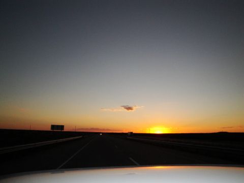 1989 Ford Taurus - Driving on the highway as the sun sets, casting a warm glow across the sky.