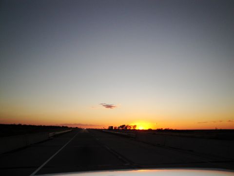 1989 Ford Taurus - A long highway leads into a colorful sunset, with a lone truck visible in the distance.