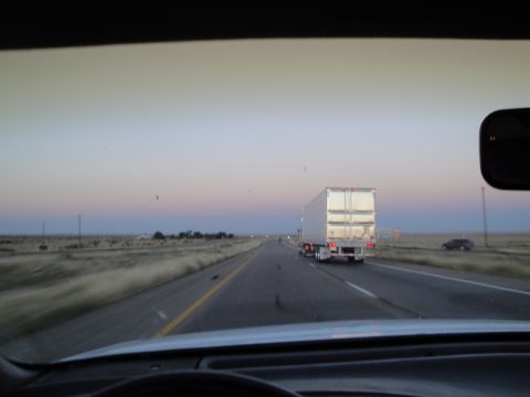 1989 Ford Taurus - View from inside a vehicle on a highway at dusk, with a semi-truck in the right lane and a car in the distance on the shoulder.