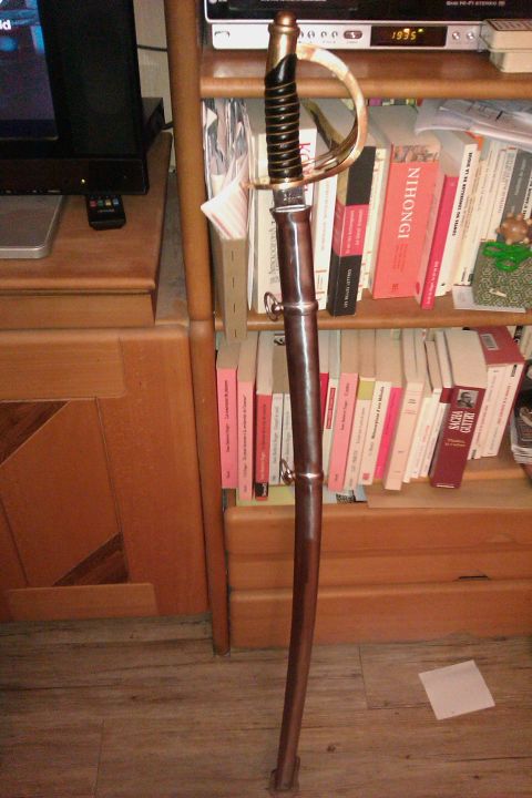 1991 Ford Crown Victoria - A sword with a brass hilt and a brown scabbard is displayed indoors.