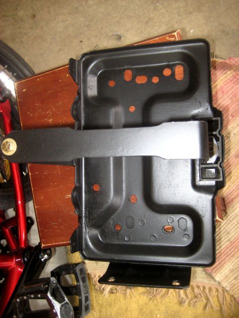 1996 Ford Bronco - A black metal battery tray with a clamp is shown, resting on a wooden surface.