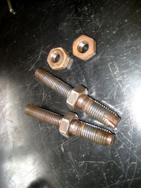 1996 Ford Bronco - Two threaded bolts and two nuts are shown on a dark, scratched surface.