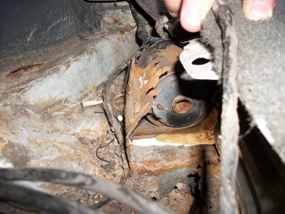 Close-up of heavily rusted metal frame and suspension component on a vehicle