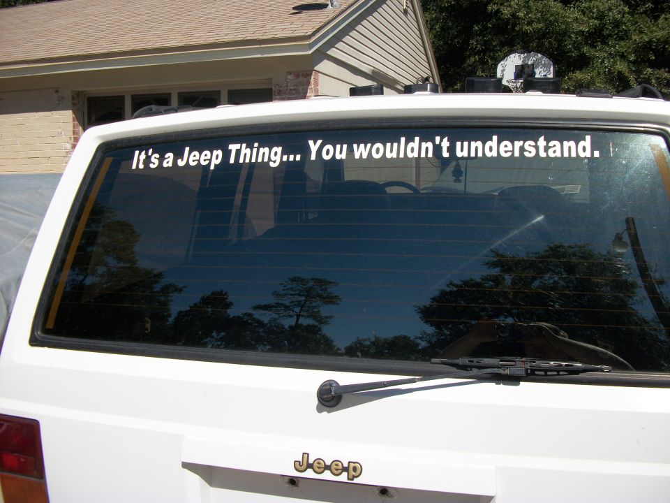 White Jeep Cherokee rear window with "It's a Jeep Thing... You wouldn't understand." sticker. Jeep logo visible below