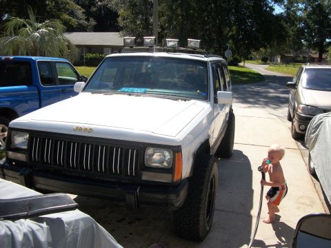 1992 Jeep Cherokee - A white 1992 Jeep Cherokee is parked in a driveway next to a blue truck and another vehicle.
