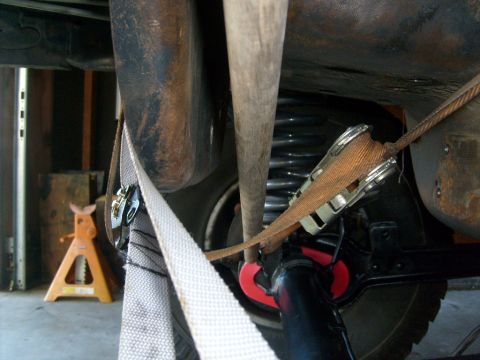 1986 Ford Bronco - A close-up view of a vehicle's undercarriage, showing straps and suspension components.