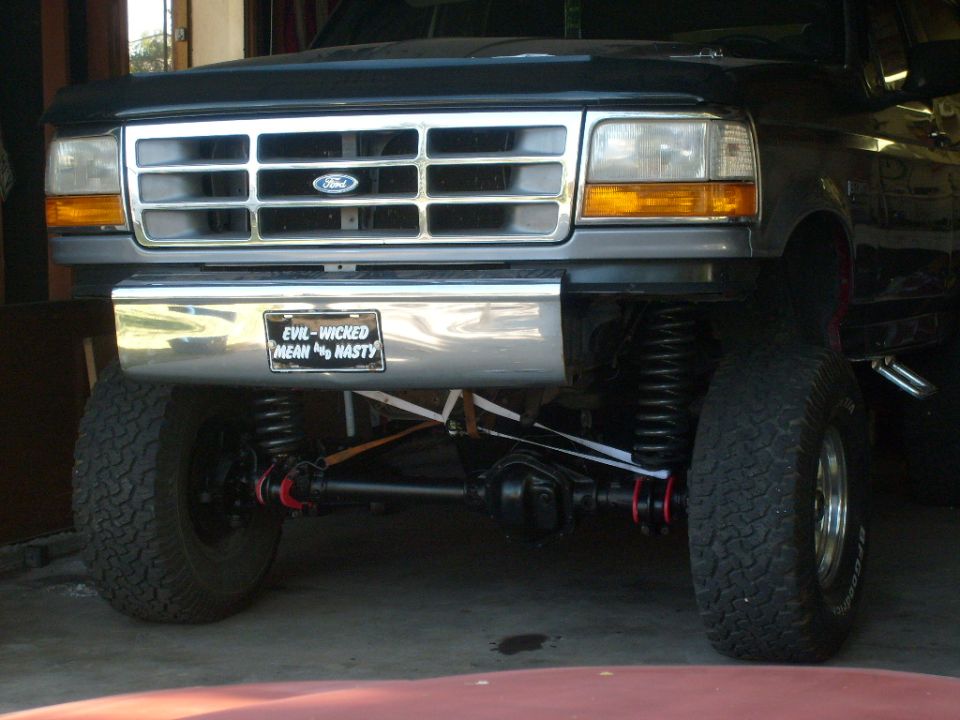 Front view of lifted Ford truck with chrome grille and a license plate that says 'EVIL-WICHED MEAN NASTY'
