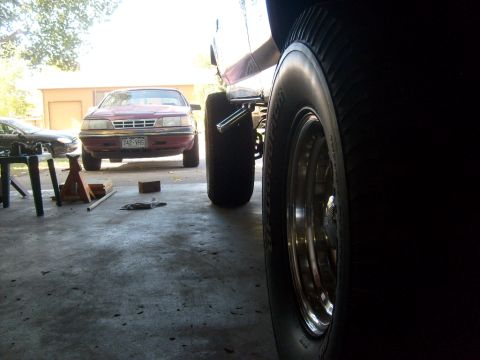 1986 Ford Bronco - Garage scene with a red sedan and a vehicle with large tires.