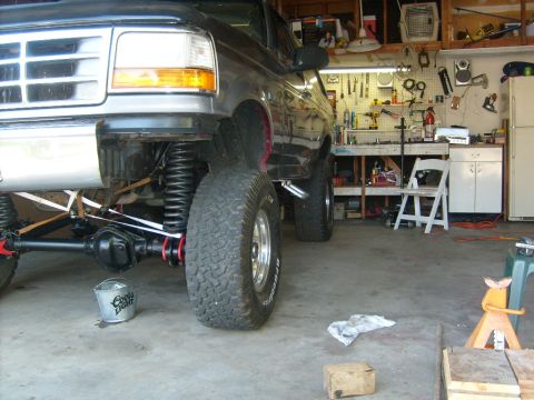 1986 Ford Bronco - Close-up of a lifted 1992 Ford Bronco's front end in a garage setting.