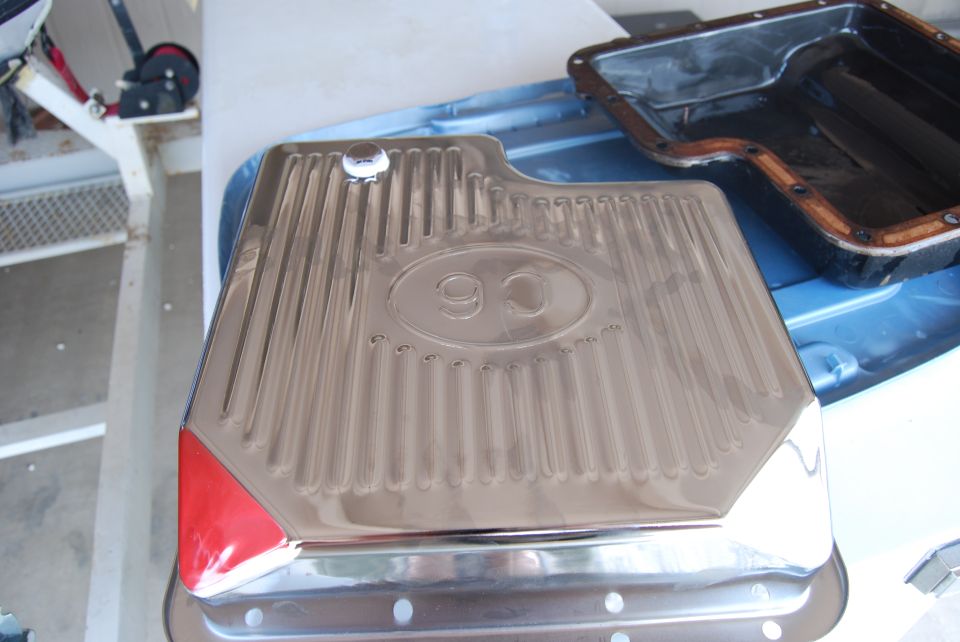 Chrome oil pan with C6 designation and red corner accent, next to a black gasket