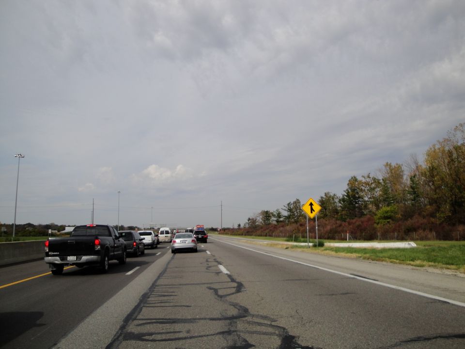 Cars and trucks on a highway with a merge lane sign