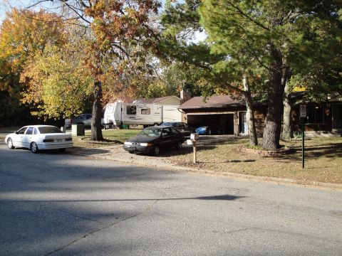 1989 Ford Taurus - A white sedan is parked on the street in front of a residential house with a driveway.