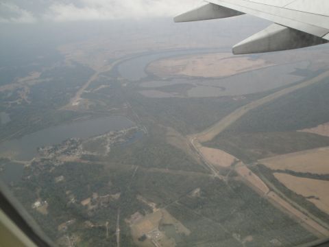 1989 Ford Taurus - View from an airplane window shows a landscape with a river, trees, and fields below.