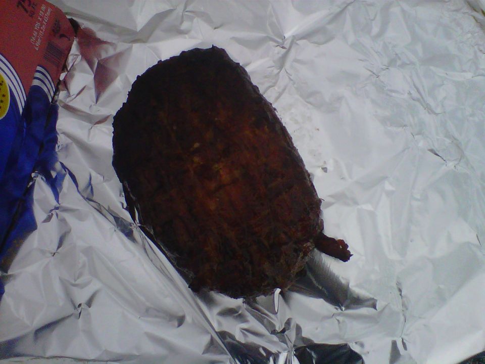 Dark scored roast on crumpled aluminum foil next to a foil box