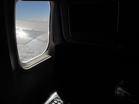 1989 Ford Taurus - Looking out an airplane window at the wing and clouds below during flight.