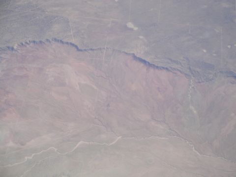 1989 Ford Taurus - An aerial perspective captures a vast desert terrain, characterized by a prominent canyon and winding, dry river channels etched into the l…