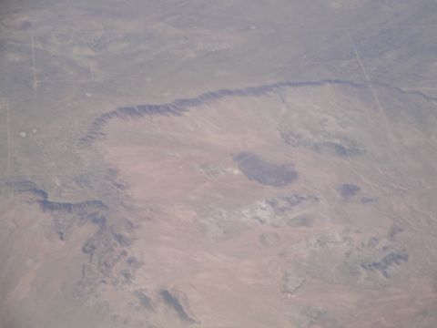 1989 Ford Taurus - An aerial perspective captures the expansive desert terrain, marked by dramatic geological formations and a distant horizon.