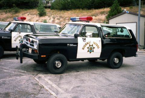 1987 Dodge 1500 - Black-and-white California Highway Patrol Dodge Ramcharger 4x4 SUV parked on cracked asphalt beside an identical second unit, shot from the…