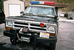 1987 Dodge 1500 - This Dodge Ram police truck features a light bar and a winch on the front bumper. The license plate is visible.