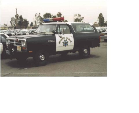 1987 Dodge 1500 - Police SUV with light bar and "Highway Patrol" markings is parked in a lot with other vehicles.