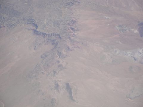 1989 Ford Taurus - Expansive desert terrain with dramatic geological formations visible from above.