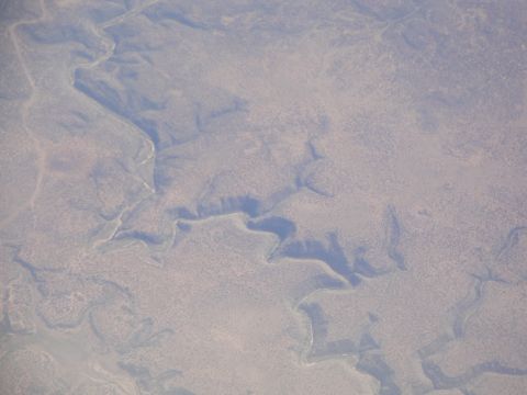 1989 Ford Taurus - An aerial perspective captures the intricate patterns of a dry, arid landscape, characterized by winding riverbeds and sparse vegetation.