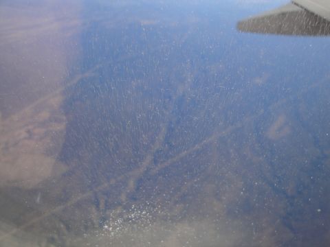 1989 Ford Taurus - View from an airplane window shows a wing and a dusty sky below.