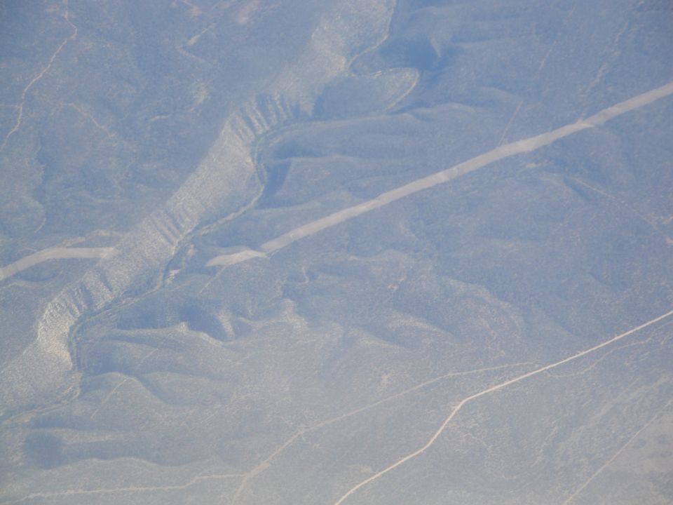 Aerial view of a winding road cutting through a dry, hilly landscape
