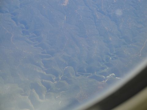 1989 Ford Taurus - An aerial perspective captures a river snaking through a vast, green mountain landscape under a hazy sky.