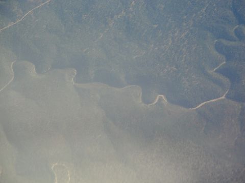 1989 Ford Taurus - A river carves a path through a vast, tree-covered landscape from an aerial perspective.