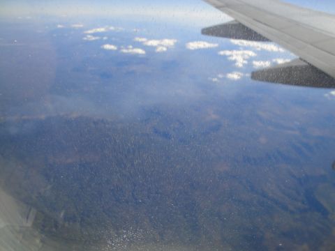 1989 Ford Taurus - View from an airplane window shows the wing and a landscape with clouds below.