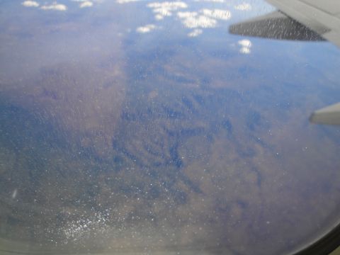 1989 Ford Taurus - Looking out the window of an airplane at the clouds and terrain below.