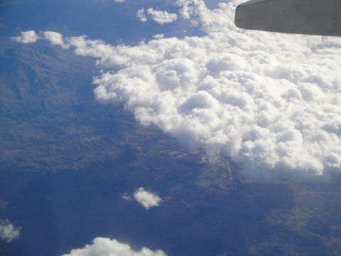 1989 Ford Taurus - View from an airplane window shows a wingtip above clouds and terrain below.
