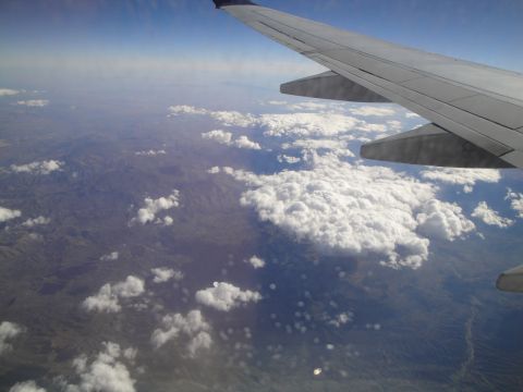 1989 Ford Taurus - View from an airplane window shows the wing and clouds over a vast landscape.